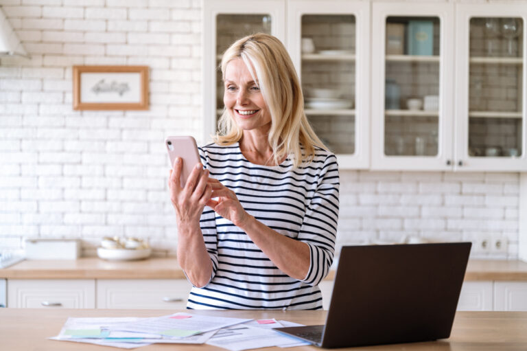 Smiling middle aged woman using smartphone for payment utility bill