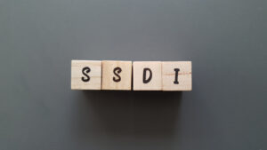 SSDI acronym made of wooden letter cubes on dark background. Social Security Disability Insurance