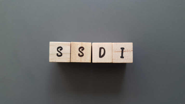 SSDI acronym made of wooden letter cubes on dark background. Social Security Disability Insurance